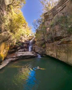 a person swimming in the water near a waterfall