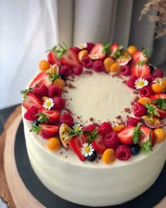 a white cake topped with fresh fruit and flowers