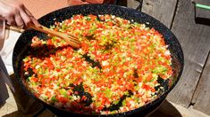 a person cooking vegetables in a large skillet