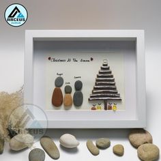 a white frame with some rocks and a christmas tree on it next to dry grass