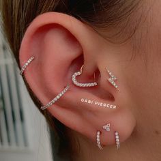 a close up of a person wearing ear piercings with the word cabi piercer written on it