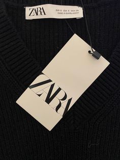 a black sweater with the name zara on it and a tag attached to it