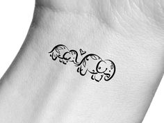 an elephant tattoo is shown on the back of someone's leg and it has two elephants