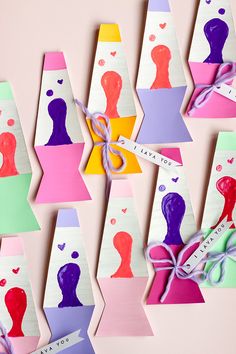 colorful paper cut outs with different shapes and colors on them, tied to strings in the shape of people's heads