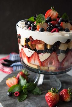 a trifle with fruit on top is sitting on a table next to strawberries