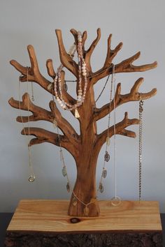 a wooden tree with many necklaces hanging from it's branches on a table