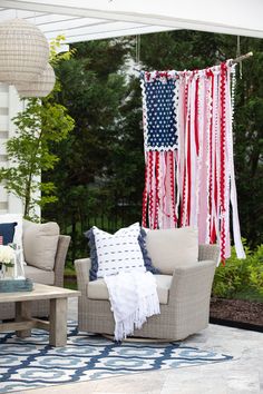 an outdoor living room with american flags hanging from the ceiling and furniture on the patio