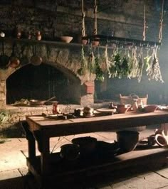 a table with pots and pans on it in front of a brick oven at night