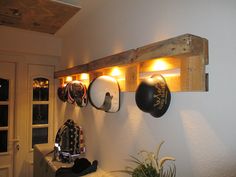 there are many hats hanging on the wall with lights above them and below it is a potted plant