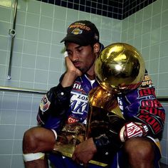 a man sitting in a bathroom next to a trophy