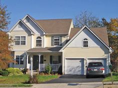 a car parked in front of a two story house with white siding and brown roof