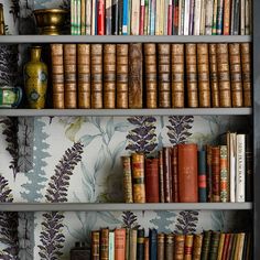 a book shelf filled with lots of books next to a vase and other decorative items