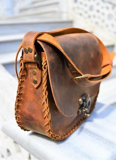 a brown leather purse sitting on top of a white bench