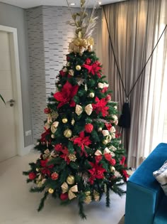 a christmas tree decorated with red and gold poinsettis in a living room