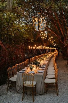 a long table set up with candles and place settings for an outdoor dinner in the evening