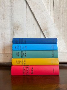 four books stacked on top of each other in front of a wooden wall and door