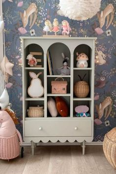 a child's room with a toy cabinet and stuffed animals on the wall behind it