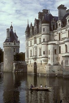 two people in a small boat on the water near an old castle