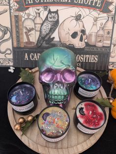 an assortment of halloween candles on a wooden plate with a skull in the middle and other items around it