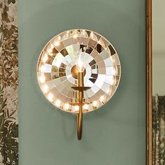 a mirror mounted on the side of a wall next to a light fixture with lights in it