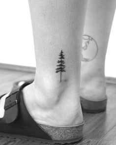 a small pine tree on the ankle tattoo is seen here in this black and white photo