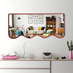 a mirror reflecting a living room with furniture and pictures on the wall above it, as well as a coffee table