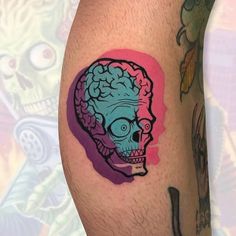 a man with a tattoo on his leg has a blue and pink skull in the shape of a human head