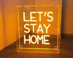 a neon sign that says let's stay home in front of a white wall