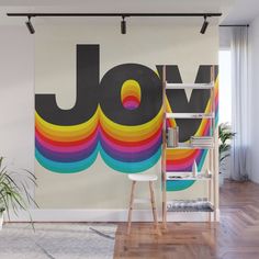 a wall mural with the word joy painted on it in black and rainbow colors next to a ladder