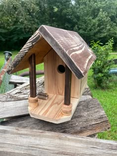 a wooden bird house sitting on top of a piece of wood