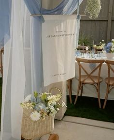 a table set up for a baby shower with blue drapes and flowers on it