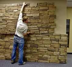 a man that is standing up against a wall with some kind of rock on it