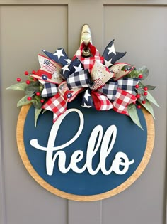 a door hanger with the word hello painted on it and an american flag bow