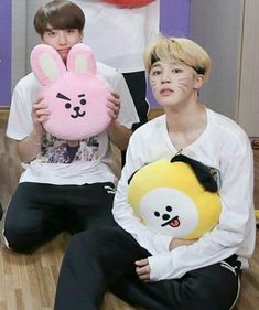 two boys sitting on the floor holding stuffed animals