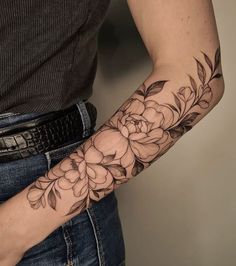 a woman's arm with flowers on it and a snake skin belt around her waist