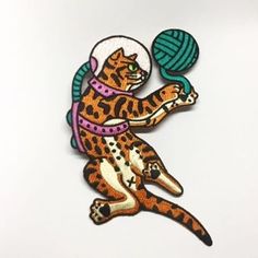 a cat is playing with a ball of yarn on a sticker that has been embroidered onto it