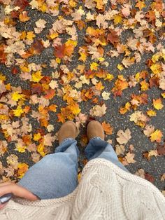 a person is standing in front of leaves on the ground with their feet propped up