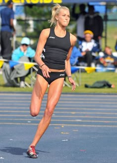 a woman running on a race track with people watching