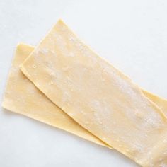 two pieces of cheese sitting on top of a white counter next to a green pepper