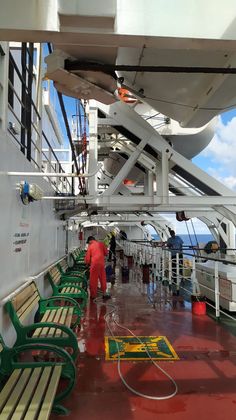 people are standing on the deck of a ship looking out at the water and some benches