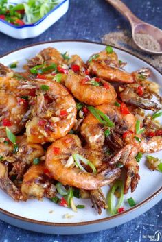 a white plate topped with fried shrimp and veggies next to a bowl of rice