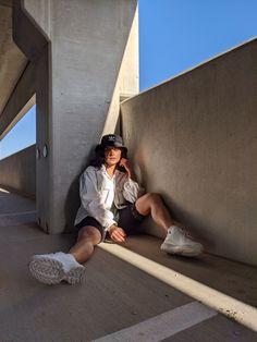 a woman sitting on the ground next to a wall