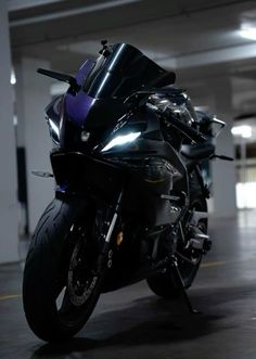 a black motorcycle parked in an empty parking garage with lights on it's side