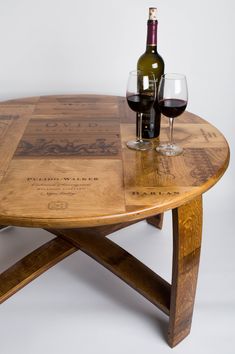 a wooden table with two wine glasses on it and a bottle of wine in the middle