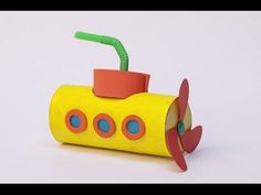 a yellow paper toy with a green straw in it's mouth