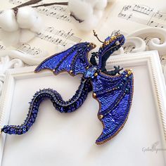 a blue dragon brooch sitting on top of sheet music