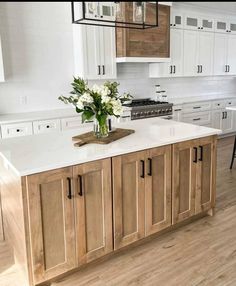 a large kitchen with white cabinets and wood flooring on the countertops, along with an island in the middle