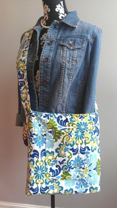 a blue jean jacket is hanging on a mannequin's dummy with a multicolored floral fabric