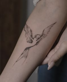 a woman's arm with a bird tattoo on it