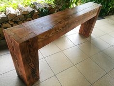 a wooden bench sitting on top of a tile floor next to a pile of logs